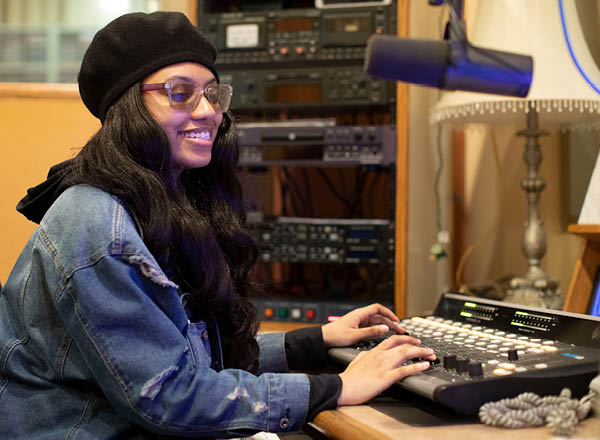 A WHFR DJ in the station, on air, sitting in front of radio equipment.